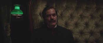 Movie still from “The Current War: Director's Cut” (2017), directed by Alfonso Gomez-Rejon – A man in a suit sitting in front of a chair; Close Up shot, Low angle