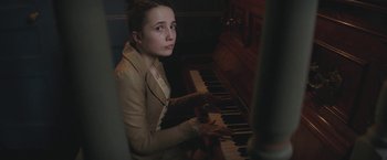 Movie still from “The Current War: Director's Cut” (2017), directed by Alfonso Gomez-Rejon – A woman sitting in front of a piano; Medium shot, High angle