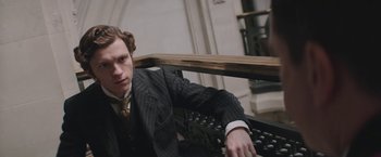 Movie still from “The Current War: Director's Cut” (2017), directed by Alfonso Gomez-Rejon – A man in a suit sitting on top of a wooden bench; Close Up shot, Low angle