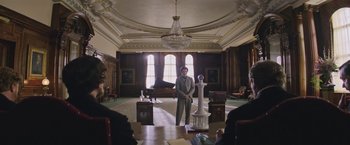 Movie still from “The Current War: Director's Cut” (2017), directed by Alfonso Gomez-Rejon – A man standing in a room with a piano and a chandelier; Wide shot, Low angle