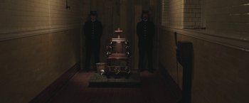 Movie still from “The Current War: Director's Cut” (2017), directed by Alfonso Gomez-Rejon – Two men standing next to a chair in a dark room; Wide shot, High angle