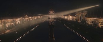 Movie still from “The Current War: Director's Cut” (2017), directed by Alfonso Gomez-Rejon – A night time view of a fountain in the middle of a park; Extreme Wide shot, High angle