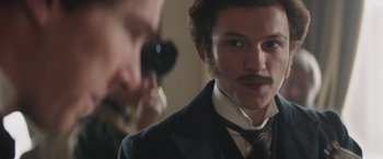 Movie still from “The Current War: Director's Cut” (2017), directed by Alfonso Gomez-Rejon – A person wearing a suit and a tie; Close Up shot, Over the shoulder angle