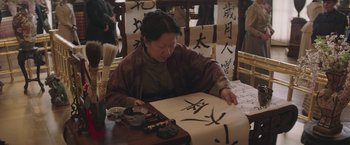 Movie still from “The Current War: Director's Cut” (2017), directed by Alfonso Gomez-Rejon – An older woman sitting at a table with a piece of paper in front of her; Medium shot, Low angle