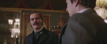 Movie still from “The Current War: Director's Cut” (2017), directed by Alfonso Gomez-Rejon – A man in a suit and tie looking at another man in a suit and tie; Medium shot, Over the shoulder angle