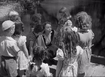 Movie still from “The Curse of the Cat People” (1944), directed by Robert Wise – A group of young children standing around a woman; Medium shot, High angle