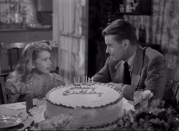 Movie still from “The Curse of the Cat People” (1944), directed by Robert Wise – A man and a woman sitting at a table with a birthday cake in front of them; Medium shot, High angle