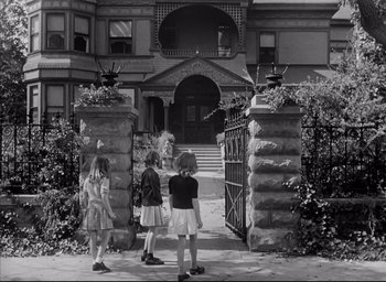 Movie still from “The Curse of the Cat People” (1944), directed by Robert Wise – Three young children are standing in front of a building; Wide shot, Low angle