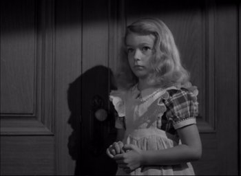 Movie still from “The Curse of the Cat People” (1944), directed by Robert Wise – A young girl standing in front of a door in a black and white photo; Close Up shot, High angle