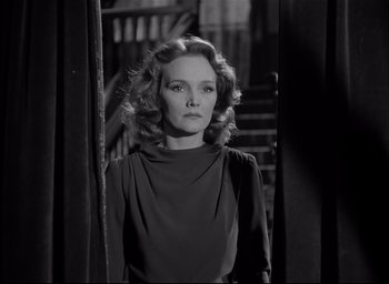 Movie still from “The Curse of the Cat People” (1944), directed by Robert Wise – A black - and - white photo of a woman standing in front of stairs; Medium shot, Low angle