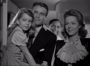 Movie still from “The Curse of the Cat People” (1944), directed by Robert Wise – A black and white photo of a man and two women and a little girl; Medium shot, Low angle