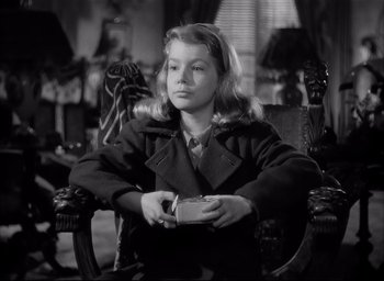 Movie still from “The Curse of the Cat People” (1944), directed by Robert Wise – A woman sitting in a chair holding a box; Medium shot, High angle
