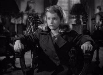 Movie still from “The Curse of the Cat People” (1944), directed by Robert Wise – A young girl sitting on a chair in a room; Medium shot, High angle