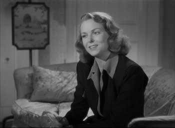Movie still from “The Curse of the Cat People” (1944), directed by Robert Wise – A woman sitting on top of a couch in a room; Medium shot, Low angle