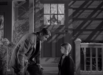 Movie still from “The Curse of the Cat People” (1944), directed by Robert Wise – A man and a woman standing next to each other in front of a building; Medium shot, Low angle