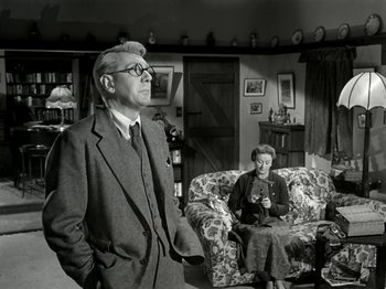 Movie still from “The Dam Busters” (1955), directed by Michael Anderson – An older man and a woman in a living room; Medium shot, Low angle