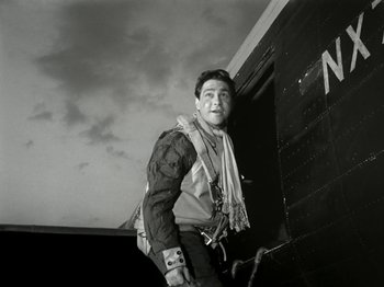 Movie still from “The Dam Busters” (1955), directed by Michael Anderson – A black and white photo of a man standing next to an airplane; Medium shot, Low angle