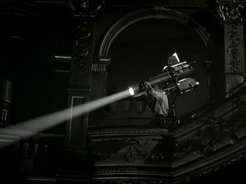 Movie still from “The Dam Busters” (1955), directed by Michael Anderson – A man is directing a movie with a projector; Wide shot, Low angle