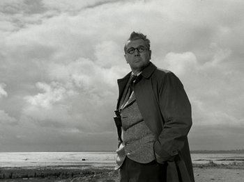Movie still from “The Dam Busters” (1955), directed by Michael Anderson – An older man standing in front of a body of water; Medium shot, Low angle