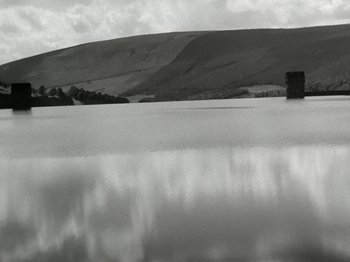 Movie still from “The Dam Busters” (1955), directed by Michael Anderson – A black and white photo of a lake and mountains in the background; Extreme Wide shot, Low angle