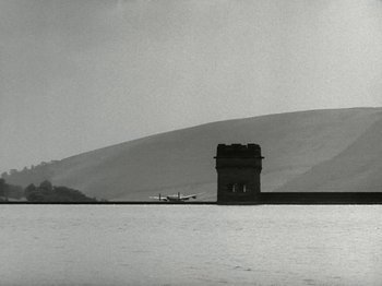Movie still from “The Dam Busters” (1955), directed by Michael Anderson – An airplane sitting on top of an airport runway; Extreme Wide shot, Low angle