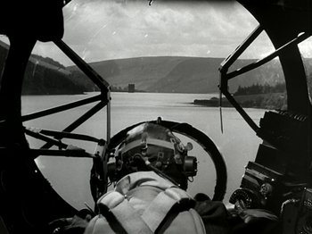 Movie still from “The Dam Busters” (1955), directed by Michael Anderson – A view from inside an airplane looking out over a body of water; Wide shot, High angle