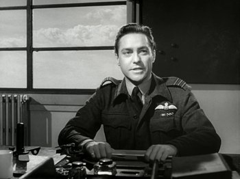 Movie still from “The Dam Busters” (1955), directed by Michael Anderson – A man sitting at a desk in front of a window; Medium shot, Low angle
