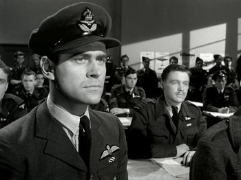 Movie still from “The Dam Busters” (1955), directed by Michael Anderson – A black and white photo of a man in a military uniform; Medium shot, Low angle