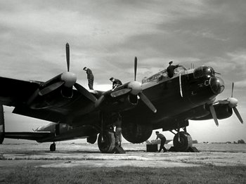 Movie still from “The Dam Busters” (1955), directed by Michael Anderson – Men working on an airplane on the ground; Wide shot, Low angle