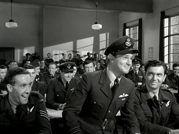 Movie still from “The Dam Busters” (1955), directed by Michael Anderson – Black and white photograph of a group of men in uniform; Medium shot, Low angle