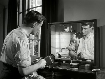 Movie still from “The Dam Busters” (1955), directed by Michael Anderson – A man looking at his reflection in a mirror; Medium shot, Low angle