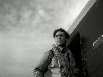 Movie still from “The Dam Busters” (1955), directed by Michael Anderson – Black and white photograph of a man with a sky background; Medium shot, Low angle