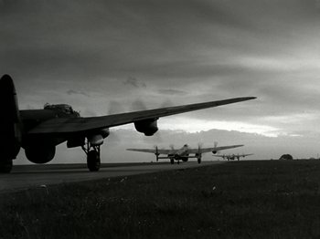 Movie still from “The Dam Busters” (1955), directed by Michael Anderson – A black and white photo of two planes on a runway; Wide shot, Low angle