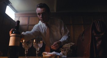 Movie still from “The Damned United” (2009), directed by Tom Hooper – A man in a white dress shirt and a tie is at a table with a sandwich and two wine glasses; Medium shot, Low angle