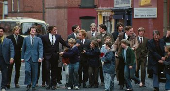 Movie still from “The Damned United” (2009), directed by Tom Hooper – A group of people walking down a street; Wide shot, Over the shoulder angle