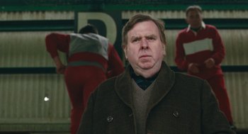 Movie still from “The Damned United” (2009), directed by Tom Hooper – A man in a brown coat and a red shirt; Close Up shot, Over the shoulder angle
