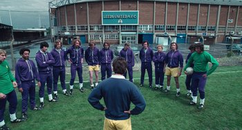 Movie still from “The Damned United” (2009), directed by Tom Hooper – A group of men standing on top of a grass covered field; Wide shot, High angle