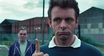 Movie still from “The Damned United” (2009), directed by Tom Hooper – A person holding a finger up; Close Up shot, Over the shoulder angle
