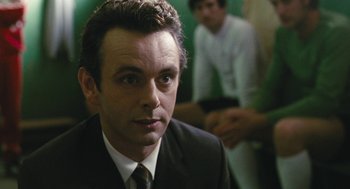 Movie still from “The Damned United” (2009), directed by Tom Hooper – A person wearing a suit and tie; Close Up shot, Over the shoulder angle