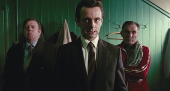 Movie still from “The Damned United” (2009), directed by Tom Hooper – A man in a suit and tie standing next to another man in a suit and tie; Medium shot, Low angle