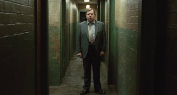 Movie still from “The Damned United” (2009), directed by Tom Hooper – A man in a suit and tie standing in an alley way; Medium shot, Low angle