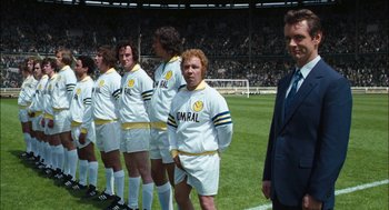 Movie still from “The Damned United” (2009), directed by Tom Hooper – A group of men standing on top of a soccer field; Medium shot, High angle