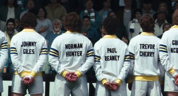 Movie still from “The Damned United” (2009), directed by Tom Hooper – A group of people standing next to each other; Medium shot, Overhead angle