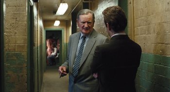 Movie still from “The Damned United” (2009), directed by Tom Hooper – A man in a suit and tie talking to another man in a suit and tie; Medium shot, Over the shoulder angle