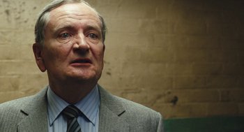 Movie still from “The Damned United” (2009), directed by Tom Hooper – An older man wearing a suit and tie; Close Up shot, Low angle