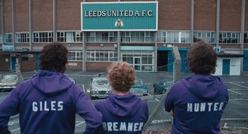 Movie still from “The Damned United” (2009), directed by Tom Hooper – A group of young men standing in front of a building; Wide shot, High angle