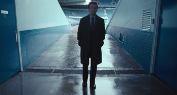 Movie still from “The Damned United” (2009), directed by Tom Hooper – A man in a suit and tie standing in a tunnel; Wide shot, Low angle