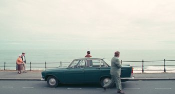 Movie still from “The Damned United” (2009), directed by Tom Hooper – A man standing next to a car on the side of the road; Extreme Wide shot, High angle
