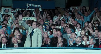 Movie still from “The Damned United” (2009), directed by Tom Hooper – A group of people in the stands at a sporting event; Wide shot, High angle