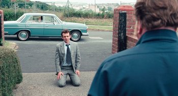 Movie still from “The Damned United” (2009), directed by Tom Hooper – A man in a suit and tie kneeling on the ground; Wide shot, High angle
